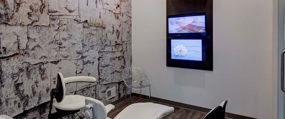 Large, Comfortable Patient Room with TVs in Front and on Ceiling Above Dental Chair
